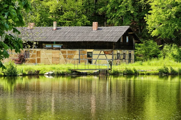 Velho celeiro de madeira por lago com ponte metálica — Fotografia de Stock