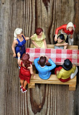 Masanın yanında oturan insanların küçük figürleri