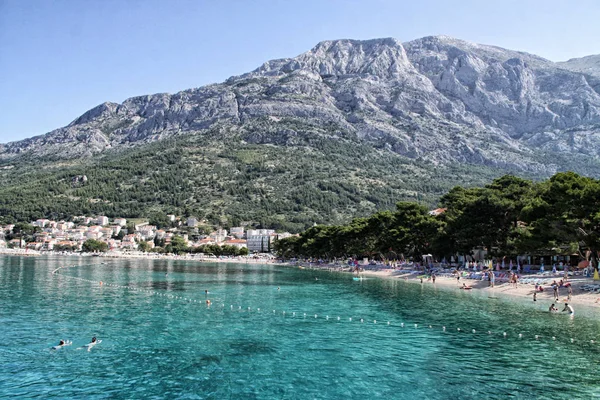 Montagne Biokovo con spiaggia rocciosa e villaggio Baska-Voda — Foto Stock