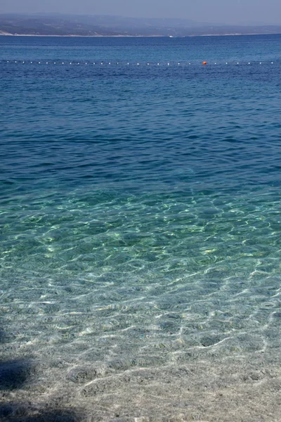 Superfície do mar pela praia de cascalho com linha de área de natação — Fotografia de Stock