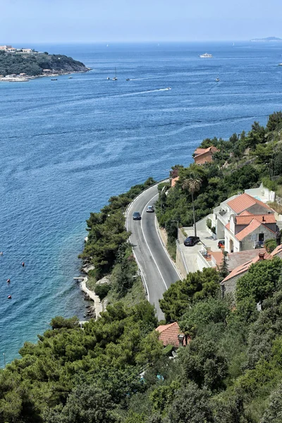Strada curva in riva al mare con case con tetto rosso — Foto Stock