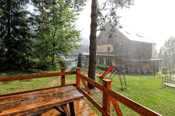 Дождь в саду с деревянной террасой — стоковое фото