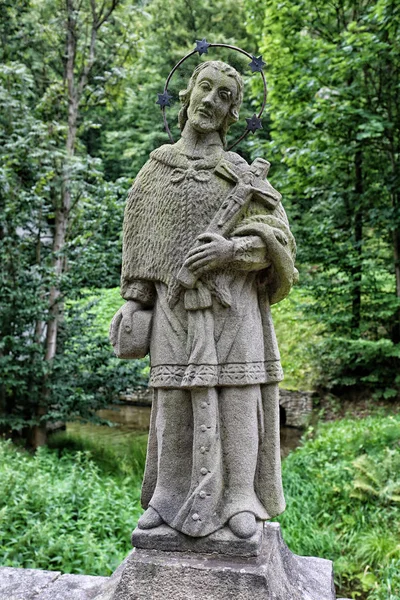Kamenná socha svatého muže s krucifix — Stock fotografie