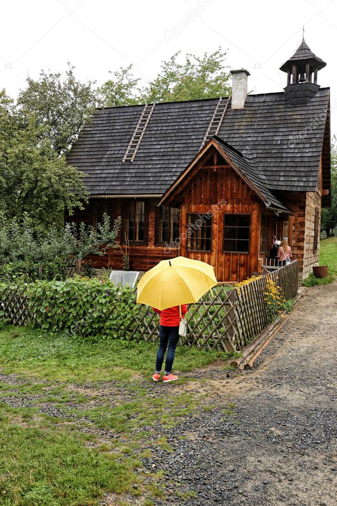 Old wooden building with lady under yellow umbrella