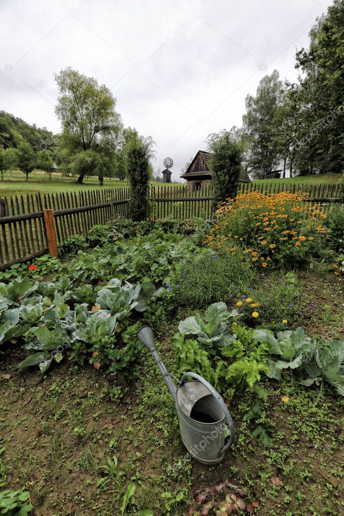 Small garden with wooden fencing around and watering can
