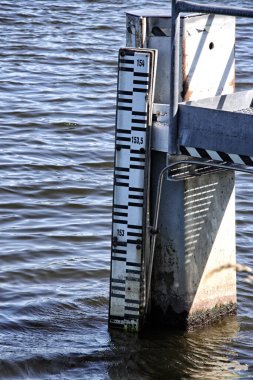 Nehirdeki direğin üzerindeki su akışı göstergesi