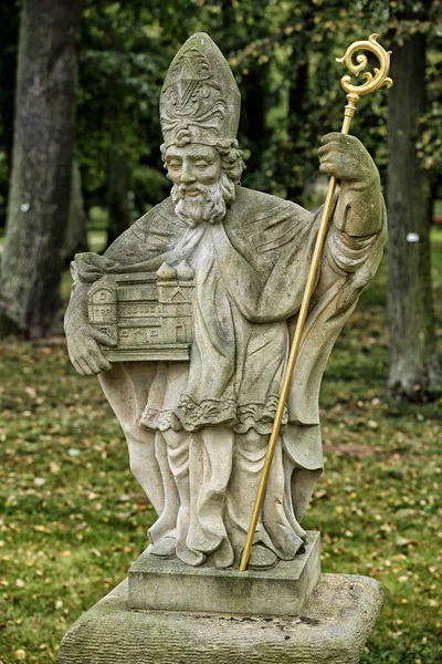 牧师在公园里手持教堂模型和金色拐杖的雕像 — 图库照片