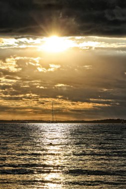 Fırtınalı bulutlarla deniz kıyısında altın gün batımı