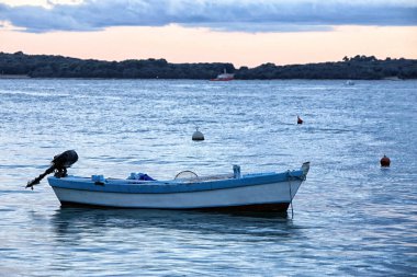 Akşamları siyah motorlu ahşap beyaz ve mavi bir tekne.