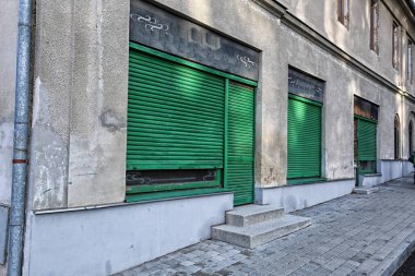 Kapalı yeşil kepenklerle kaplı eski dükkan pencereleri