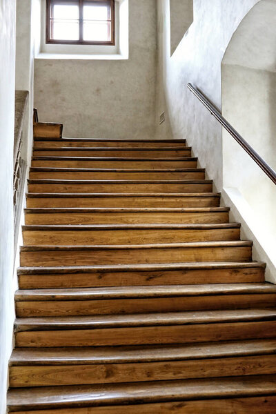 Wooden stairway in the palace interior with dirty white walls