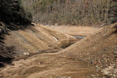 Issız Orlik su barajının vadisi. Dik kumlu kıyıları ve terk edilmiş tekneleri var.