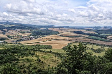 Bulutlu yaz gününde tarlaları ve ormanlarıyla Kuzey Bohemya kırsalında