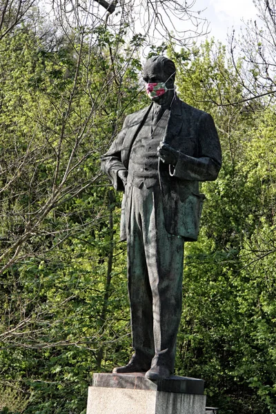 Large statue of the man in suit wearing  face mask