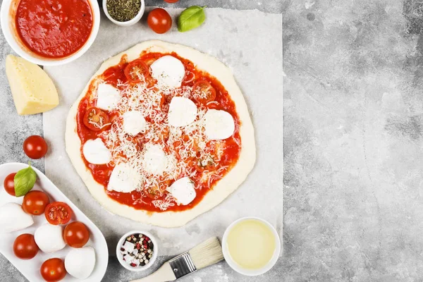 Pizza dough and ingredients for pizza on gray background. Top view, copy space. Food background