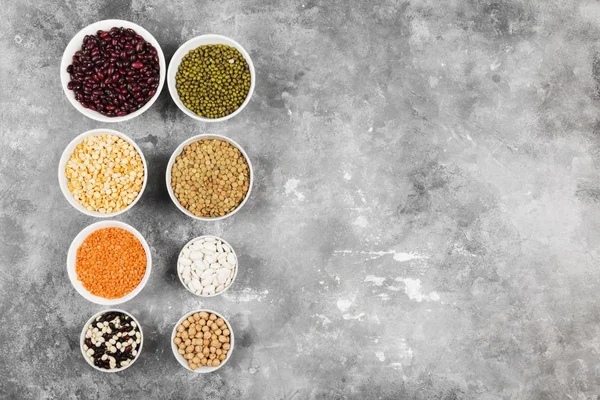 Fasulye ürün yelpazesine (kırmızı mercimek, yeşil mercimek, nohut, bezelye, Kuru fasulye, fasulye, mix fasulye, mung fasulye) gri arka plan üzerinde. Görünümü en çok, uzay kopyalayın. Gıda arka plan