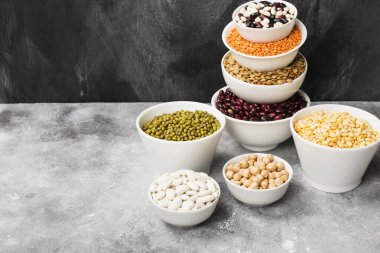 Fasulye ürün yelpazesine (kırmızı mercimek, yeşil mercimek, nohut, bezelye, Kuru fasulye, fasulye, mix fasulye, mung fasulye) gri arka plan üzerinde. Uzay kopyalayın. Gıda arka plan