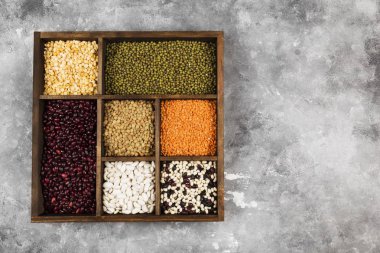 Fasulye ürün yelpazesine (kırmızı mercimek, yeşil mercimek, nohut, bezelye, Kuru fasulye, fasulye, mix fasulye, mung fasulye) gri arka plan üzerinde. Görünümü en çok, uzay kopyalayın. Gıda arka plan