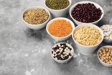 Fasulye ürün yelpazesine (kırmızı mercimek, yeşil mercimek, nohut, bezelye, Kuru fasulye, fasulye, mix fasulye, mung fasulye) gri arka plan üzerinde. Uzay kopyalayın. Gıda arka plan