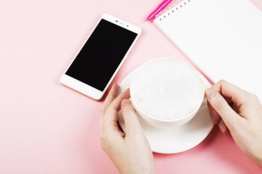 Kadın kapuçino içiyor. Planlama (kapuçino, defter, kalem, telefon) kavramı sabah. Uzay kopyalayın. Gıda arka plan