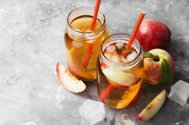 Şeftali nektarin buz çay lemonad farklı malzemeler iki bardak gri arka plan üzerine kavanoz. Uzay kopyalayın. Gıda arka plan