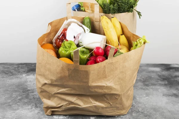 Various healthy food in paper bag on gray background