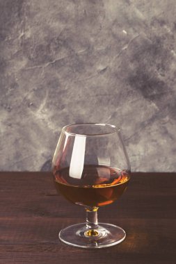 Ahşap arka plan üzerinde cam konyak. Tonda