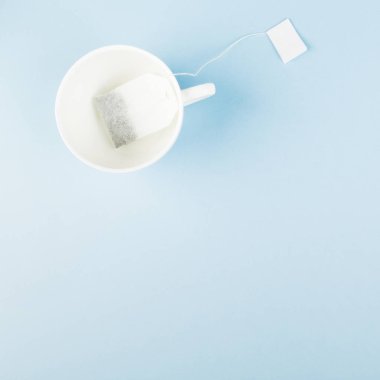 Mavi arka planda bir fincan çay ve çay poşeti. Üst görünüm, kopyalama alanı