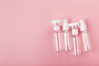 Seyahat küçük şişe pembe bir arka plan üzerinde ayarlayın. Üstte görünüm, kopya spa
