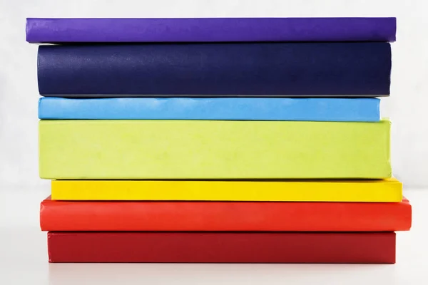 Pilha de livros coloridos arco-íris sobre fundo branco — Fotografia de Stock