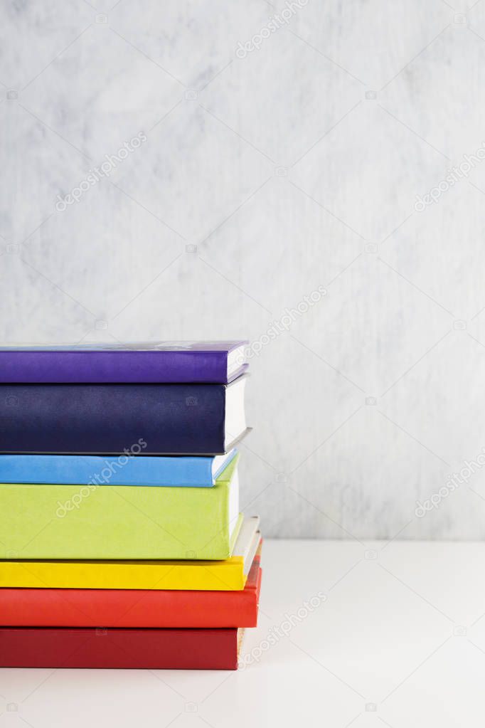 Stack of colorful rainbow books on white background. Copy space