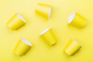 Sarı arka plan üzerinde sarı kağıt bardak