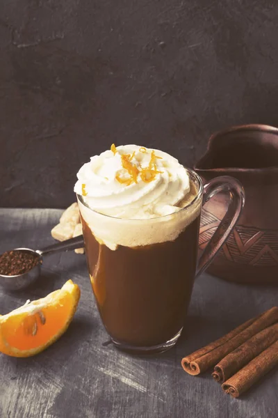 Autumn drink of coffee with orange juice and cream on dark backg