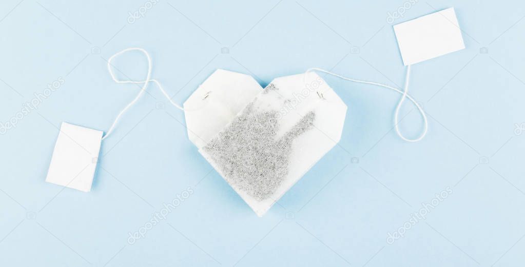 Tea bags in form of heart on blue background. Top view. Food bac