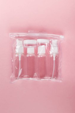 Seyahat küçük şişe pembe bir arka plan üzerinde ayarlayın. Üstte görüntü