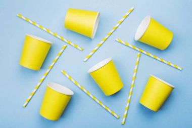 Sarı kağıt bardak ve mavi arka plan üzerinde sarı-beyaz saman. Sayfanın Üstü