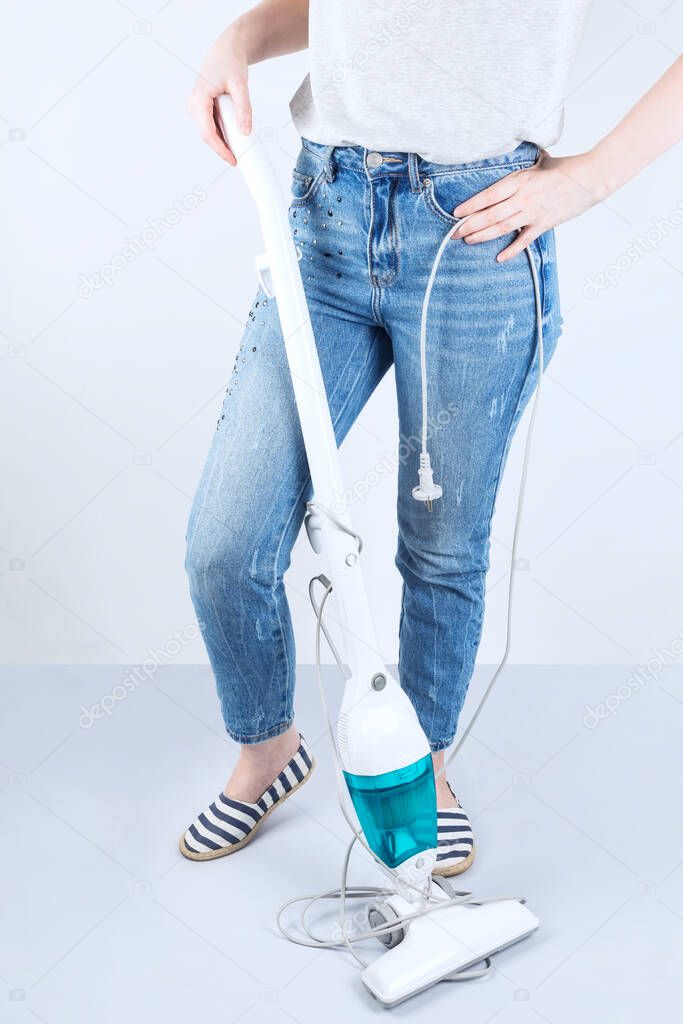 Concept wireless vacuum cleaners, wire interferes, inconvenience. Girl stands next to vacuum cleaner on the floor long tangled wire