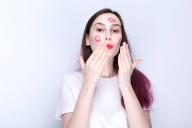 Yüzünde kırmızı ruj izi olan ve hava öpücüğü veren mutlu genç bir kız. Dünya Öpüşme Günü Konsepti