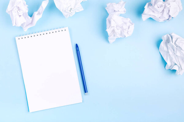 Белая тетрадь и ручка на синем фоне вокруг скомканной бумаги. Концепция начала составления плана, отбрасывания плохих идей. Плоский лежал. Копирование пространства
