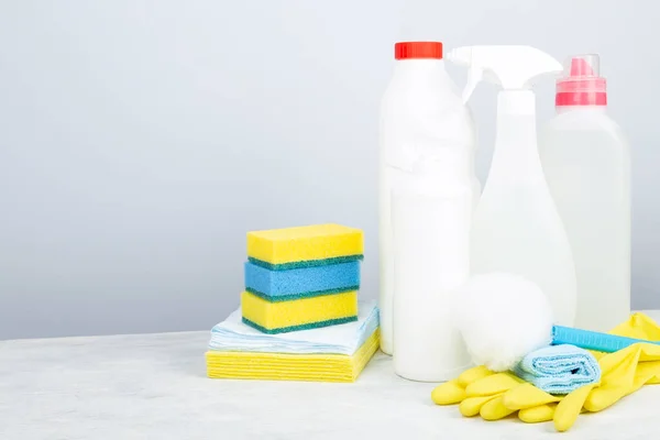 Various detergents and cleaning products agent, sponges, napkins and rubber gloves, gray background. Copy space