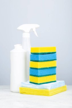 Çeşitli deterjan ürünleri, sünger yığını ve temizlik peçeteleri, pembe arka plan.