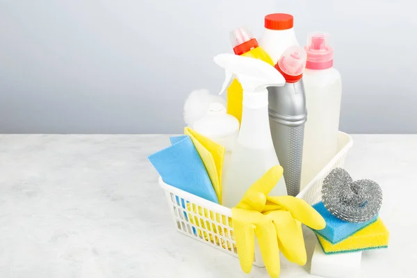 Various detergents and cleaning products agent, sponges, napkins and rubber gloves, gray background. Copy space