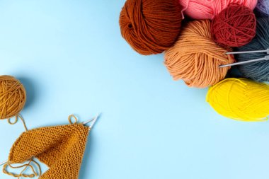 Örgü örmek için renkli iplik, mavi arka plan. Örgü projesi devam ediyor. Üst Manzara. Boşluğu kopyala