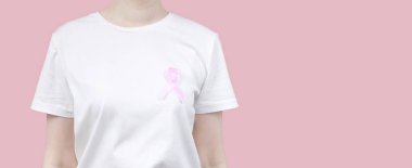 Dünya Göğüs Kanseri Günü konsepti. Beyaz tişörtlü kadın elinde pembe kurdele tutuyor. Ekim Kanser Farkındalığı Ayı. Boşluğu kopyala