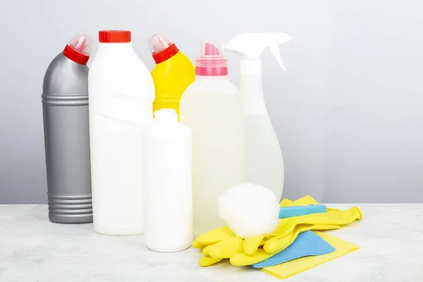 Various detergents and cleaning products agent, sponges, napkins and rubber gloves, gray background. Copy space