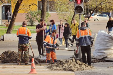 Çalışan insanlar, inşaatçılar zemin ve asfalt kazıyorlar.