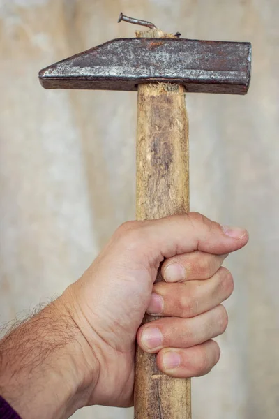 Textured hammer with a curved nail in the hand of a man