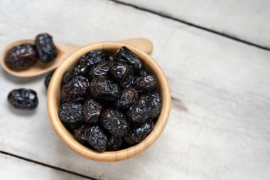 Ajwah, beyaz ahşap arka plandaki ahşap bir kasede, Müslümanlar için oruç kırmak için kullanılan meyvelerdir..