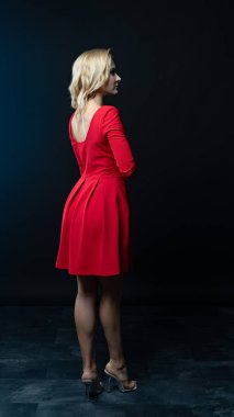 Siyah arka planda poz veren kırmızı elbiseli güzel bir kadın.