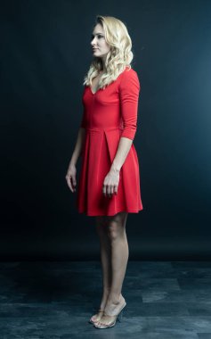 Kırmızı elbiseli güzel sarışın kadın. Stüdyo. koyu arkaplan.